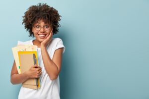 agreable-femme-afro-americaine-tient-blocs-notes-papiers-etudes-universite-heureuse-terminer-ses-etudes