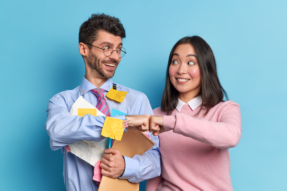 cheerful-mixed-race-woman-man-colleagues-celebrate-successfully-finished-work-make-fist-bump-pose-with-paper-documents-look-gladfully-each-other