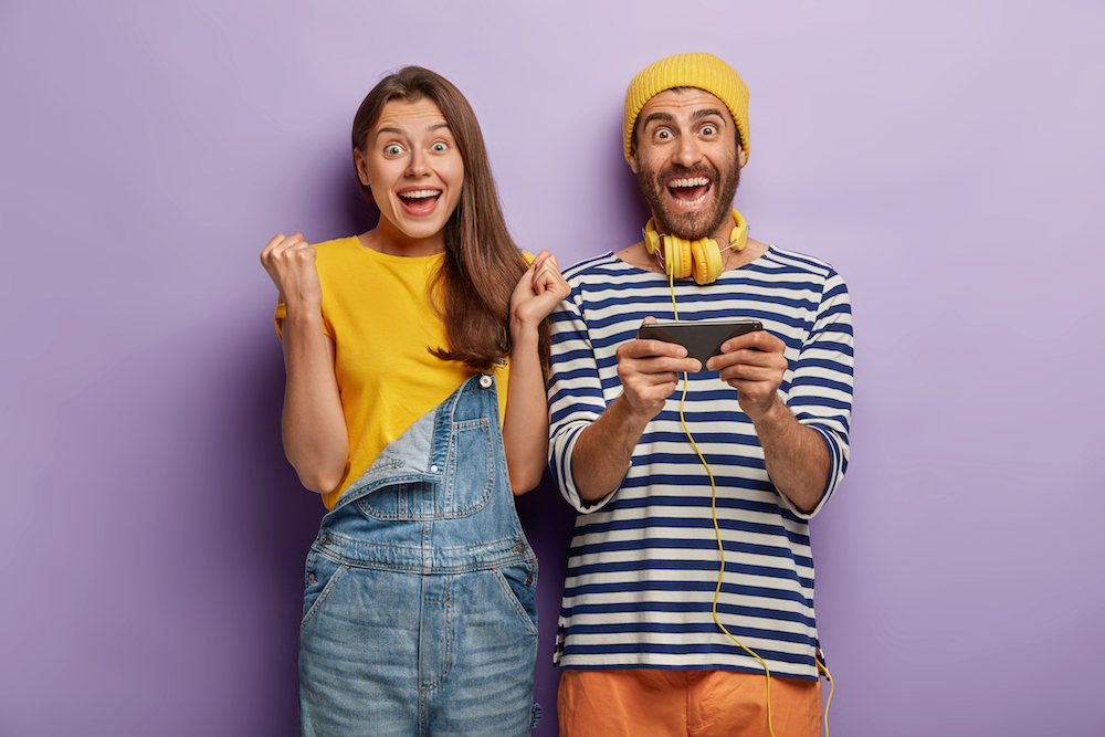 happy-cheering-woman-rejoice-man-holds-smartphone-horizontally