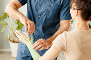Smiling Rehabilitation Therapist Putting Physio Tape