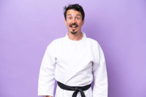 young-caucasian-man-doing-karate-isolated-purple-background-with-surprise-facial-expression
